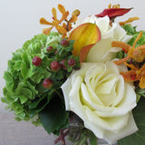 Flowers used: white roses, orange calla lilies, orange mokara orchids, green hydrangeas, hypericum berries