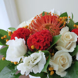 Flowers used: cream roses, white lisianthus, red celosias, orange protea, orange berries
