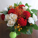 Flowers used: cream roses, white lisianthus, red celosias, orange protea, orange berries