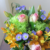 Flowers used: blush pink roses, orange orchids, red tulips, green chrysanthemums, blue aster daisies