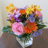 Flowers used: blush pink roses, orange gerberas, yellow, orange and mauve orchids, blue aster daisies