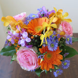 Flowers used: blush pink roses, orange gerberas, yellow, orange and mauve orchids, blue aster daisies