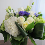 Flowers used: white roses, green and white hydrangeas, green chrysanthemums, purple ranunculus, white lisianthus