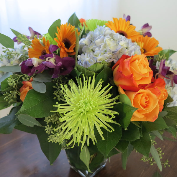 Flowers used: orange roses, orange gerberas, blue hydrangeas, green chrysanthemums, purple orchids, seeded eucalyptus