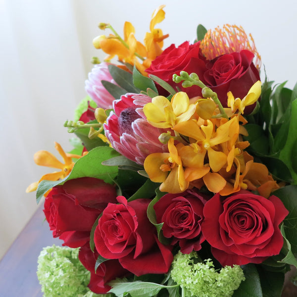 Flowers used: red roses, orange orchids, green viburnum, orange and pink protea