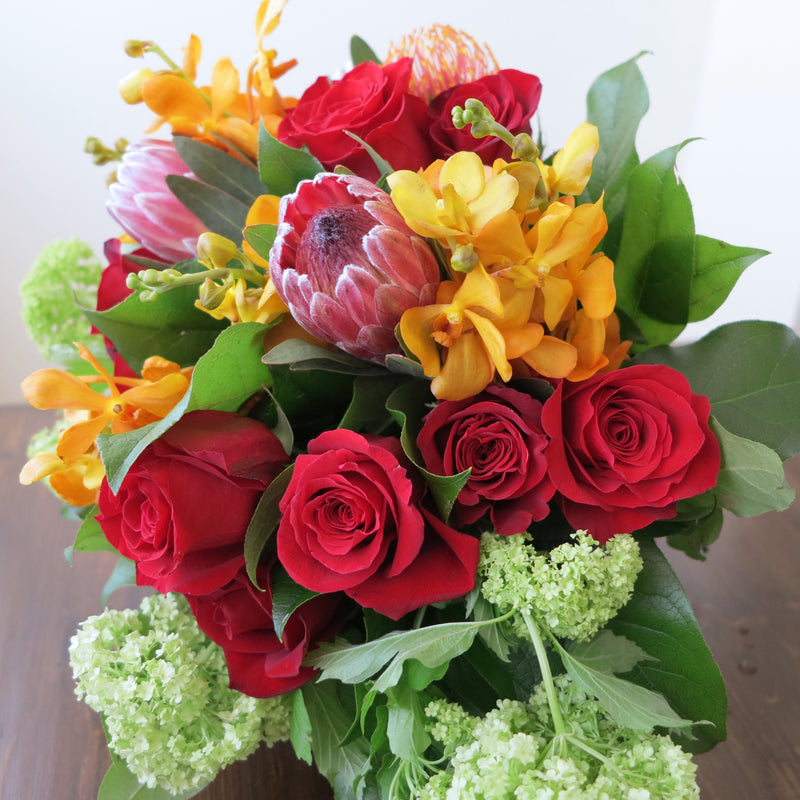 Flowers used: red roses, orange orchids, green viburnum, orange and pink protea