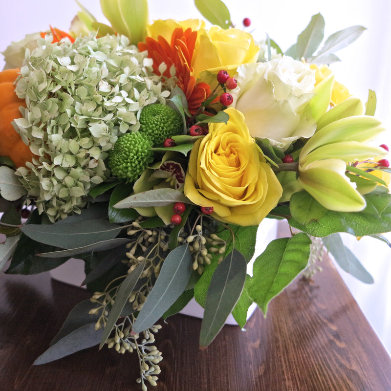 Flowers used: yellow roses, orange gerberas and gourds, green mums, orchids and hydrangeas, red rose hips and chartreuse seeded eucalyptus