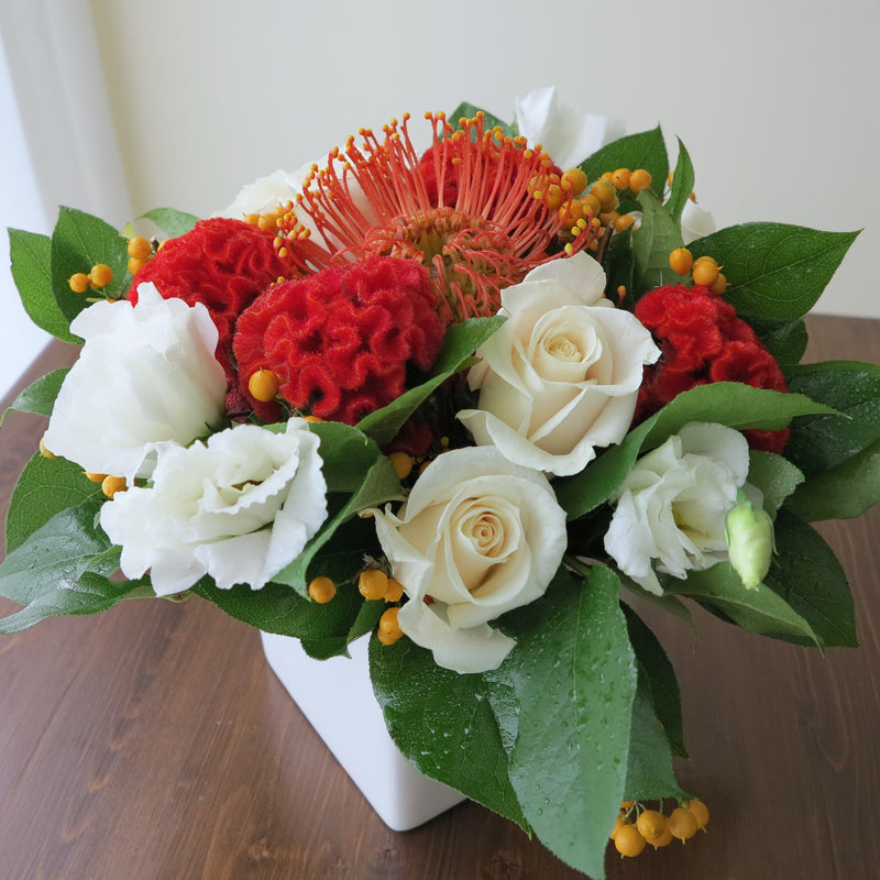 Flowers used: cream roses, white lisianthus, red celosias, orange protea, orange berries