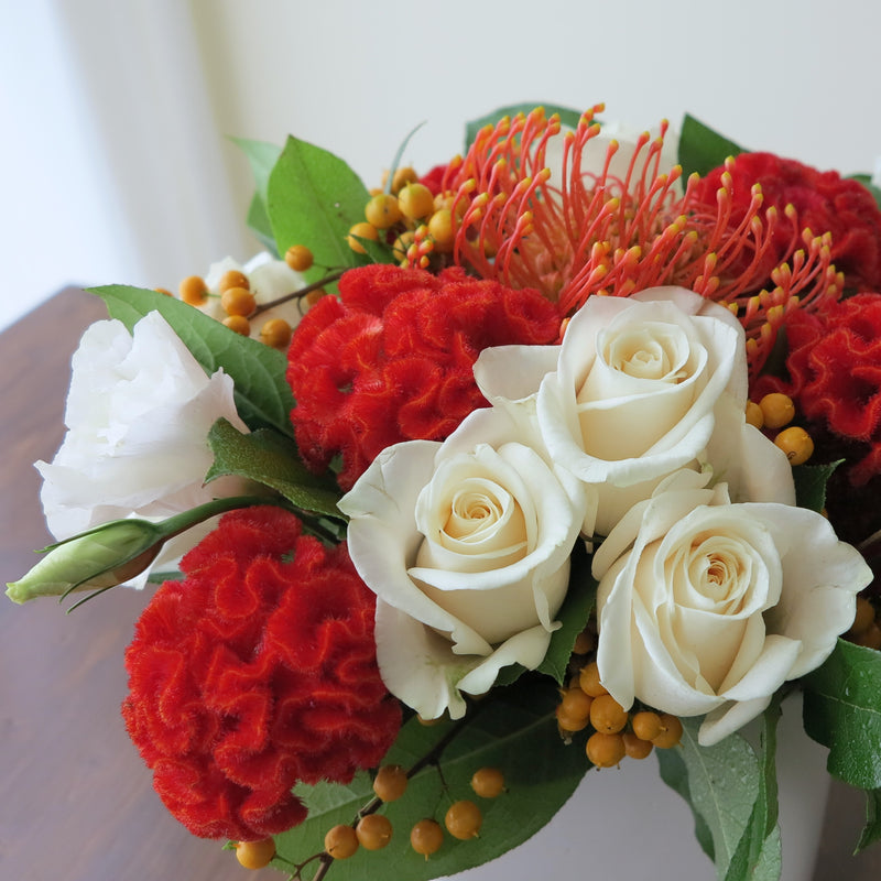 Flowers used: cream roses, white lisianthus, red celosias, orange protea, orange berries