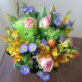Flowers used: blush pink roses, orange orchids, red tulips, green chrysanthemums, blue aster daisies