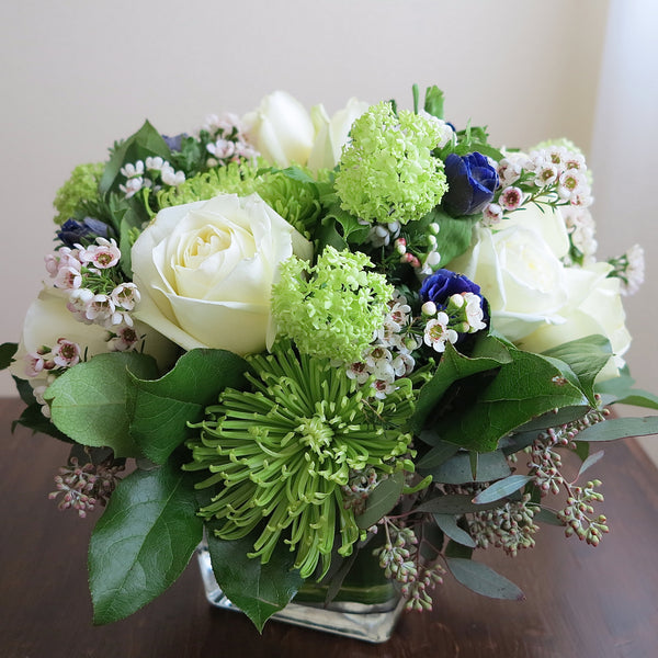 Flowers used: white roses, green chrysanthemums and viburnums blue/purple anemones, wax flowers, seeded eucalyptus