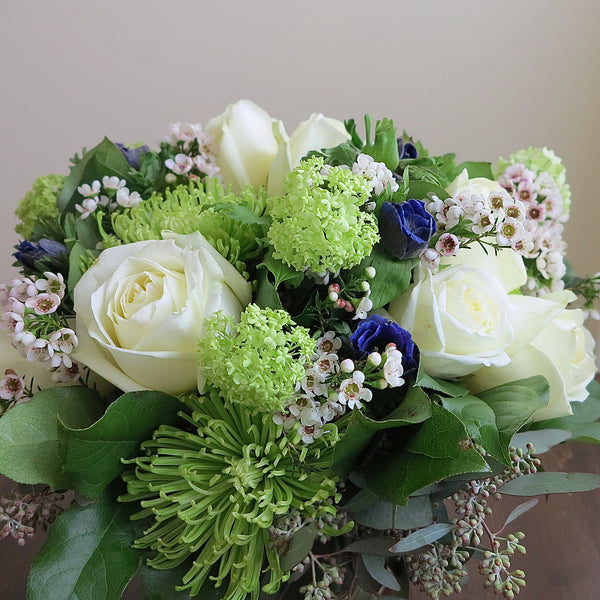 Flowers used: white roses, green chrysanthemums and viburnums blue/purple anemones, wax flowers, seeded eucalyptus