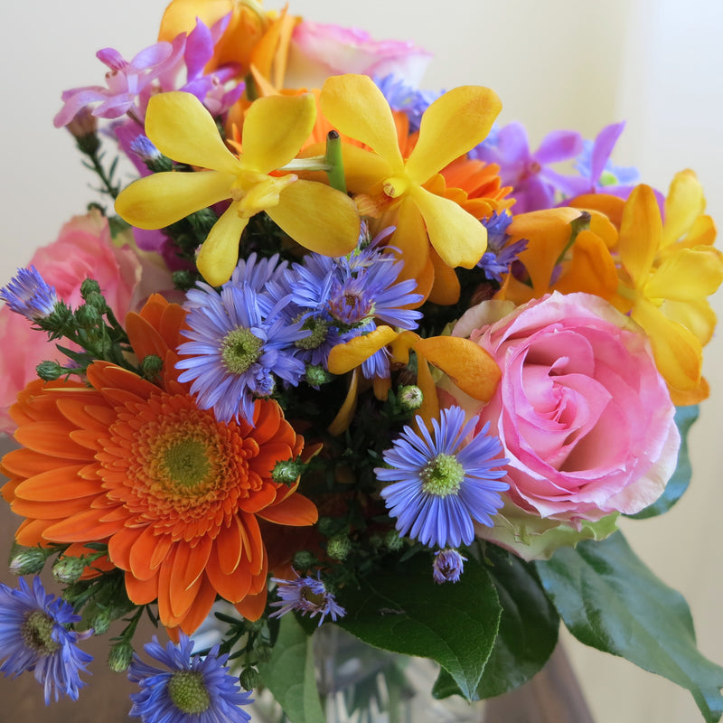 Flowers used: blush pink roses, orange gerberas, yellow, orange and mauve orchids, blue aster daisies