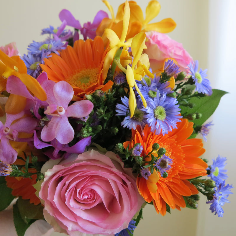 Flowers used: blush pink roses, yellow, orange and mauve orchids, orange gerberas, blue daisies
