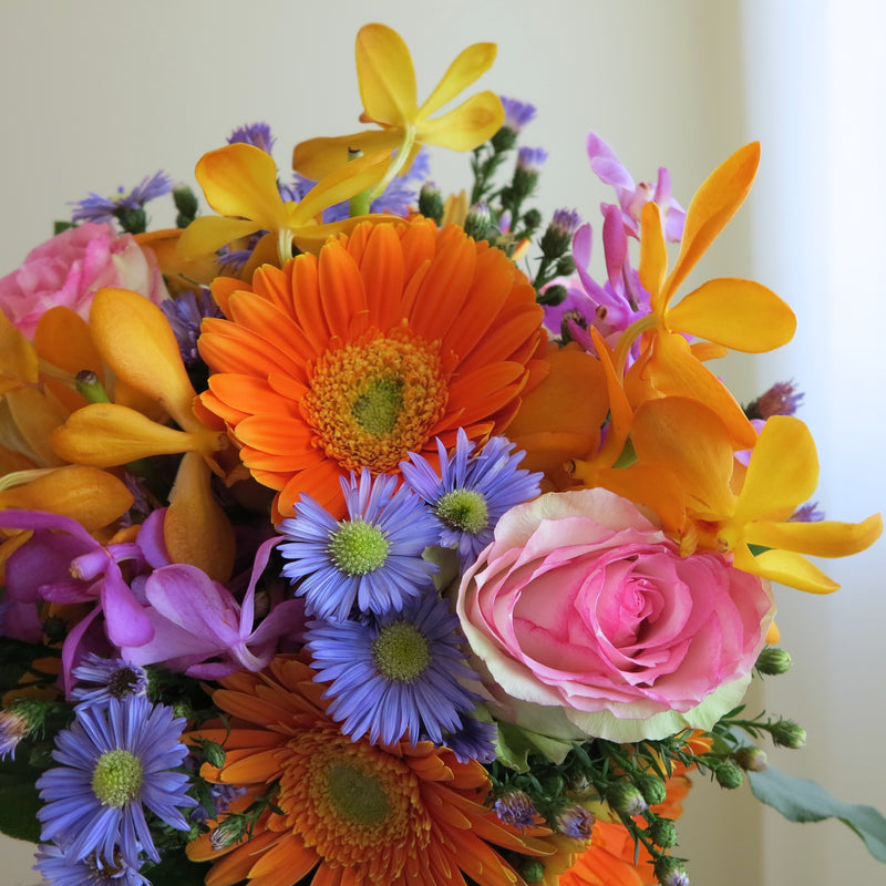 Flowers used: blush pink roses, yellow, orange and mauve orchids, orange gerberas, blue daisies